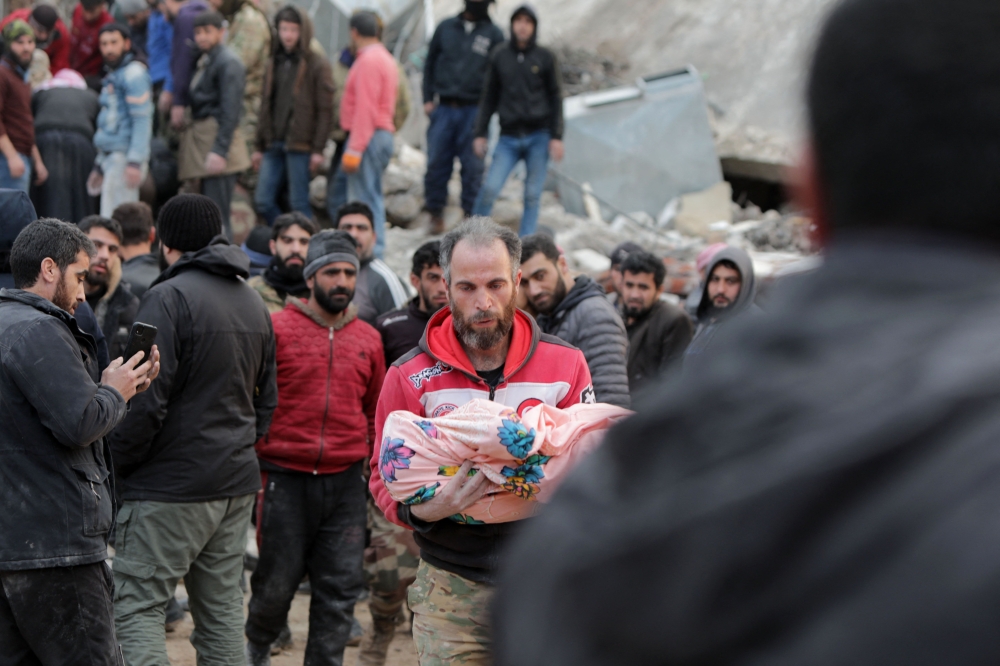  A Syrian man carries the body of a child on February 7, 2023, Photo by Bakr ALKASEM / AFP
