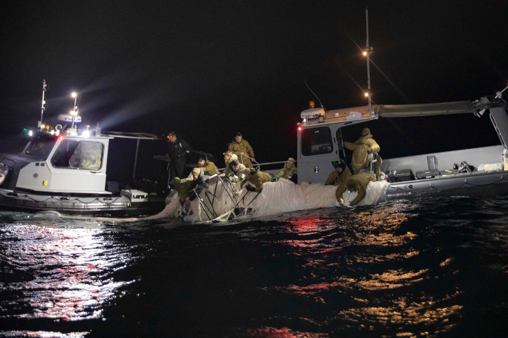 This picture provided by the US Navy shows sailors assigned to Explosive Ordnance Disposal Group 2 recover a high-altitude surveillance balloon off the coast of Myrtle Beach, South Carolina, in the Atlantic ocean on February 5, 2023.  (Photo by Petty Officer 1st Class Tyler Thompson / US NAVY / AFP) 