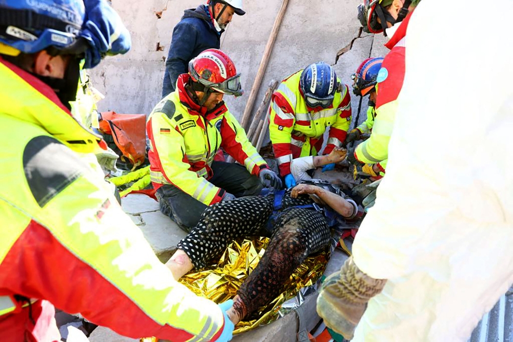 This photo taken and handed out on February 10, 2023 by the German relief organisation ISAR shows members of their rescue teams saving a woman from the rubble of a collapsed building in Kirikhan, Turkey, more than 100 hours after an earthquake hit Turkey and Syria.