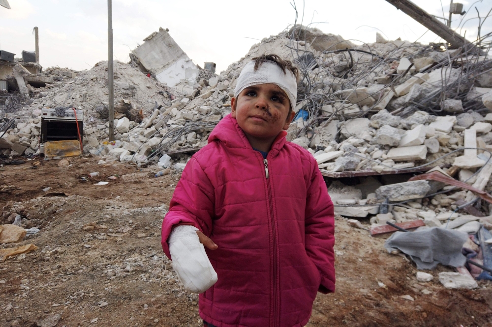 Musa Hmeidi, a Syrian child who was pulled out alive from under the rubble of a collapsed building on February 10, 2023, four days after a deadly earhquake hit the area, in the rebel-held town of Jindayris, in the rebel-held part of Aleppo province, is pictured in front of the building from which he was rescued. (Photo by Bakr ALKASEM / AFP)