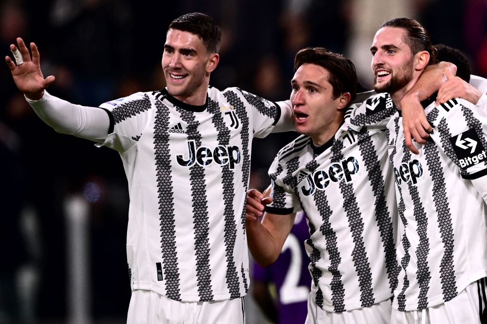 Juventus' French midfielder Adrien Rabiot (right) celebrates with Juventus' Serbian forward Dusan Vlahovic (left) and Juventus' Italian forward Federico Chiesa after opening the scoring during the Italian Serie A football match between Juventus and Fiorentina on February 12, 2023 at the Juventus stadium in Turin. (Photo by Marco BERTORELLO / AFP)
