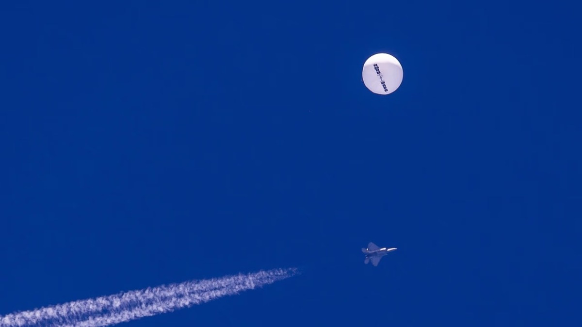 A large balloon drifts above the Atlantic Ocean, just off the coast of South Carolina, with a fighter jet and its contrail seen below it on February 4, 2023. (AP/Chad Fish)