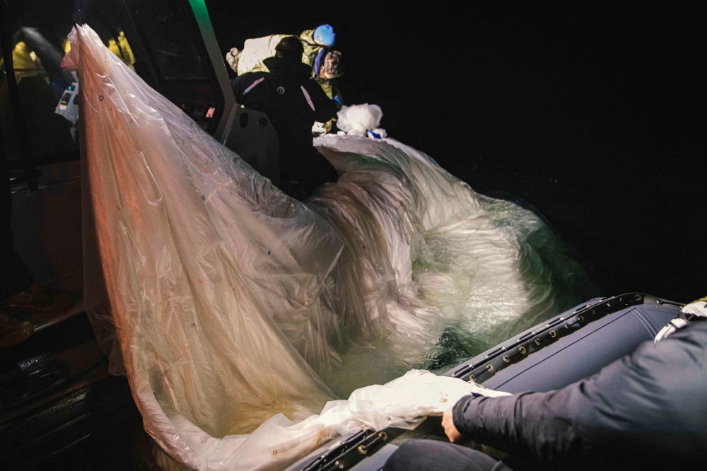 In this photo taken on February 5 2023, and obtained from the US Navy, sailors assigned to Explosive Ordnance Disposal Group 2 recover a high-altitude surveillance balloon off the coast of Myrtle Beach, South Carolina. Photo by Tyler Thompson / US NAVY / AFP
