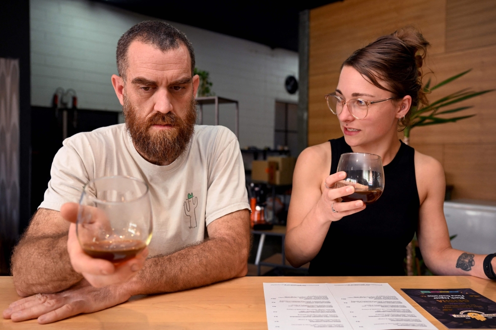 This photo taken on February 9, 2023, shows Proud Mary owner Nolan Hirte (L) and project manager Brodie Roberts (R) sampling a brew of coffee at their cafe in Melbourne. (Photo by William West / AFP) 