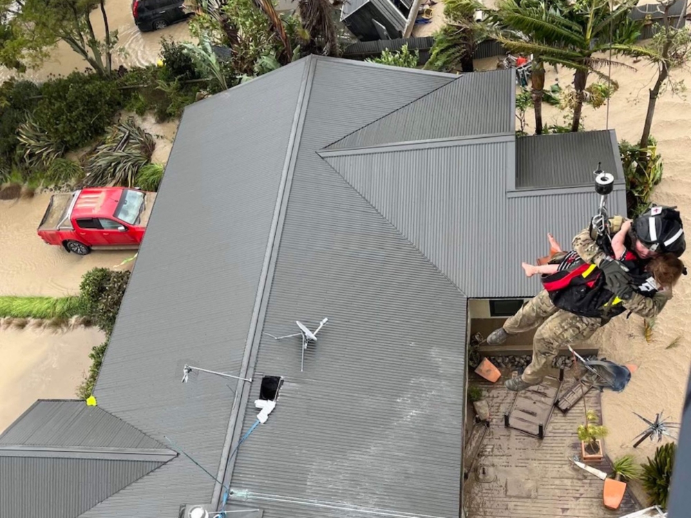 A handout photo taken and received on February 14, 2023 from the New Zealand Defence Force shows stranded people being air lifted from their rooftop by a military helicopter in the Esk Valley, near the North Island city of Napier. Photo by Handout / New Zealand Defence Force / AFP