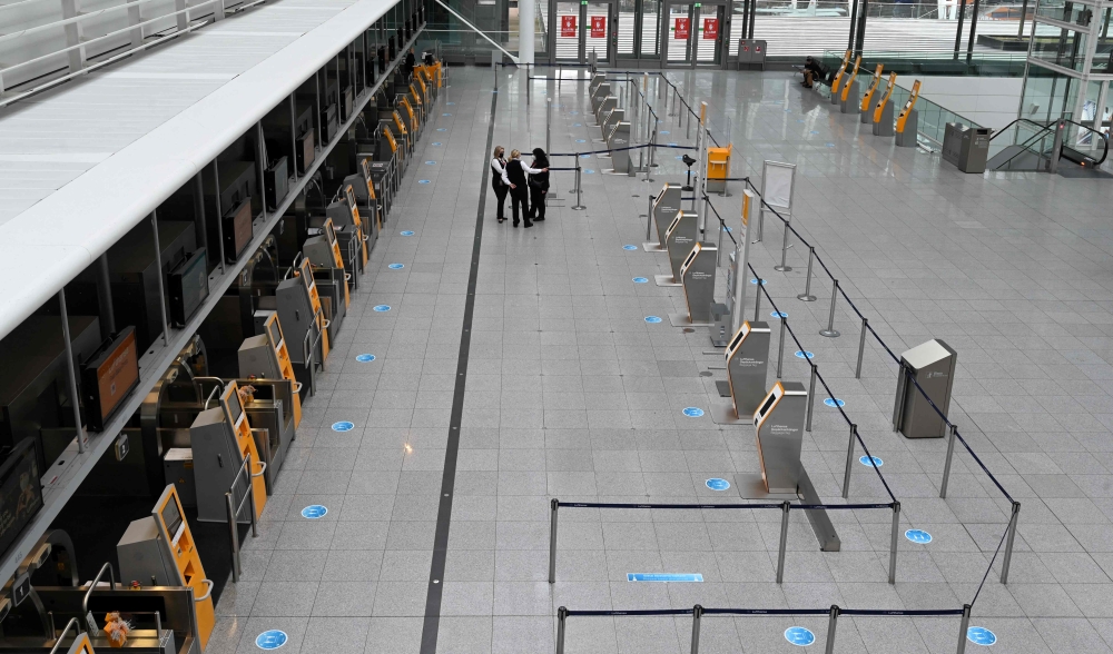 (FILES) In this file photo taken on January 25, 2022 employees wait in front of empty terminal counters of the Franz-Josef-Strauss airport in Munich, southern Germany. - More than 700 passenger flights will be cancelled at Munich airport on February 17, 2023 because of a strike by ground staff and security crew, just as the city is to host the Munich Security Conference. (Photo by Christof STACHE / AFP)
