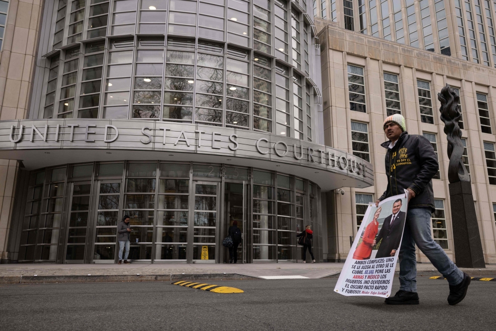 A man protests outside the courthouse where the closing arguments for the trial of the former Mexican Secretary of Public Security Genaro Garcia Luna is held in the Brooklyn borough of New York City on February 15, 2023. - Luna is accused of taking bribes to allow the notorious Sinaloa cartel to smuggle cocaine when he was public security minister during Felipe Calderon's 2006-2012 presidency. (Photo by Yuki IWAMURA / AFP)