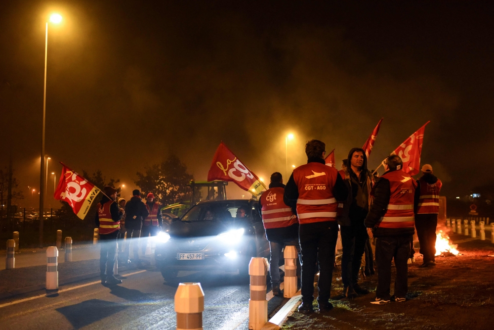 General Confederation of Labour (CGT) unionists participate to a slow-down operation against the pension reform, near Nantes' airport in Bouguenais, western France on February 16, 2023. (Photo by Sebastien SALOM-GOMIS / AFP)