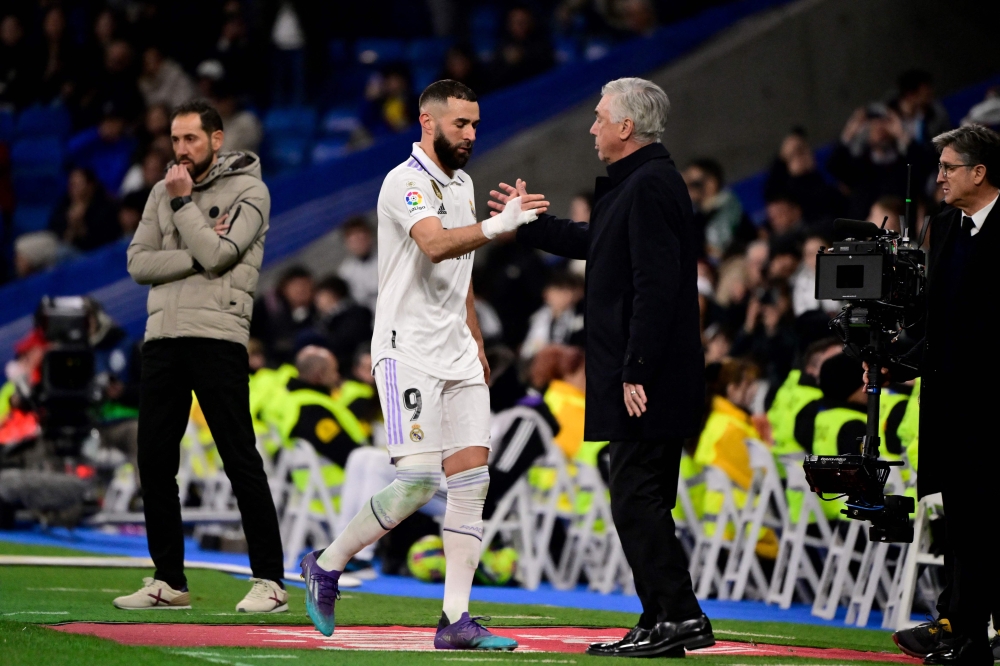 Real Madrid's French forward Karim Benzema shakes hands with Real Madrid's Italian coach Carlo Ancelotti as he leaves the pitch during the Spanish League match between Real Madrid CF and Elche CF at the Santiago Bernabeu stadium in Madrid on February 15, 2023. (Photo by JAVIER SORIANO / AFP)