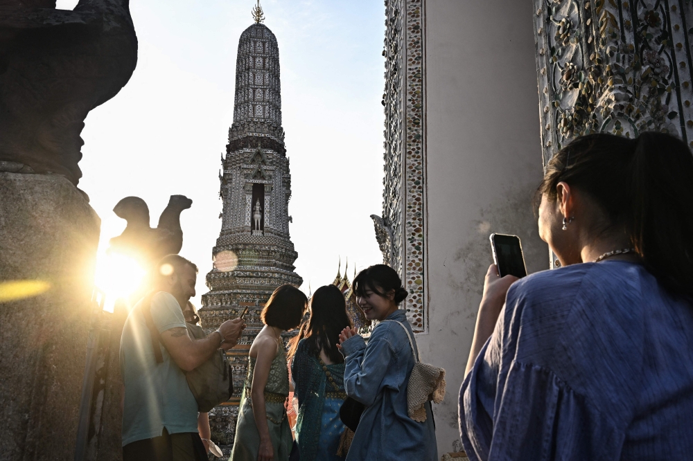  In this file photo taken on December 9, 2022 tourists take pictures at Wat Arun Buddhist temple in Bangkok. Photo by Lillian SUWANRUMPHA / AFP