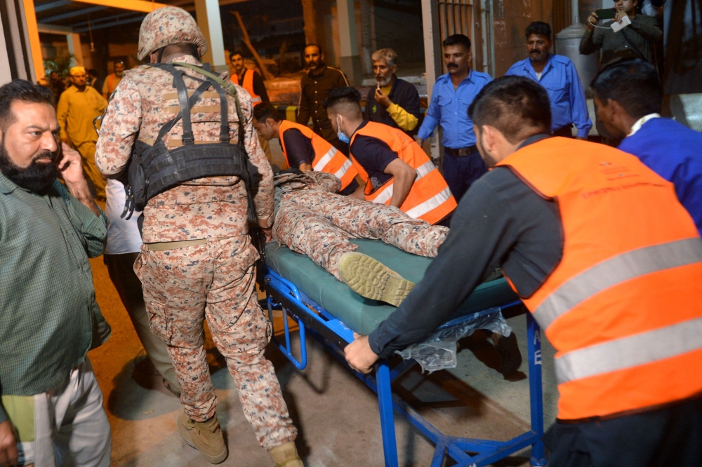Volunteers carry an injured paramilitary soldier to a hospital following an attack on a police compound in Karachi on February 17, 2023. (Photo by Rizwan Tabassum / AFP)