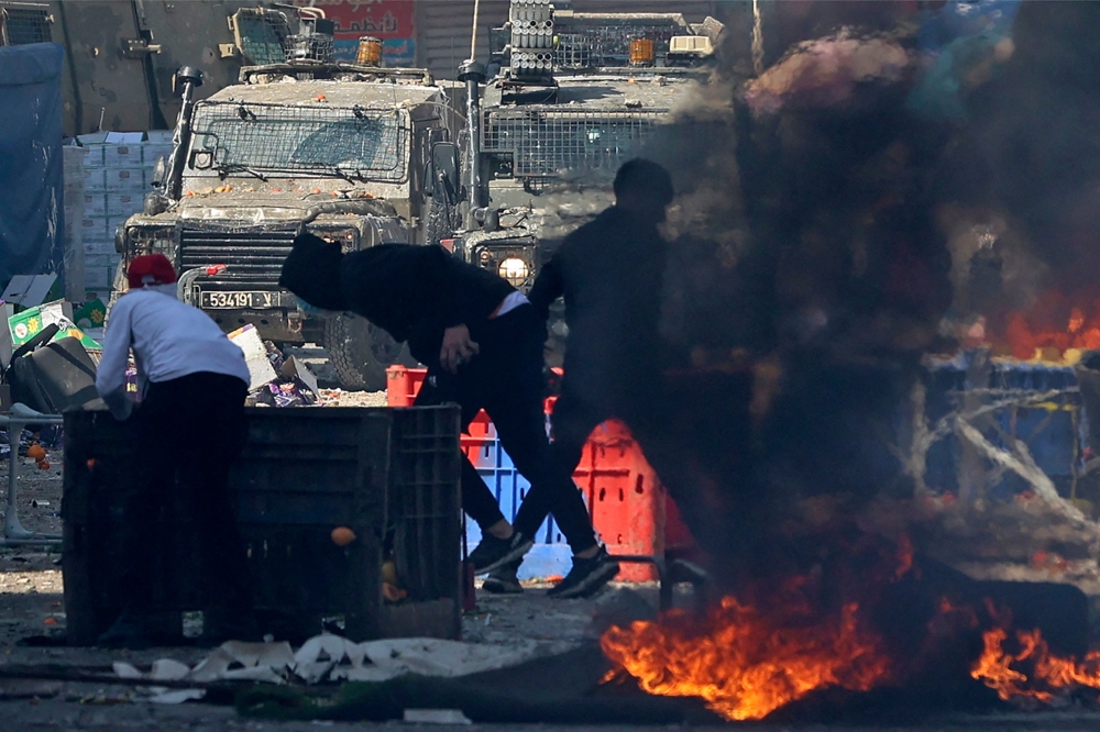 Palestinians clash with Israeli security forces during a raid in the occupied West Bank city of Nablus, on February 22, 2023. (Photo by Zain Jaafar / AFP)