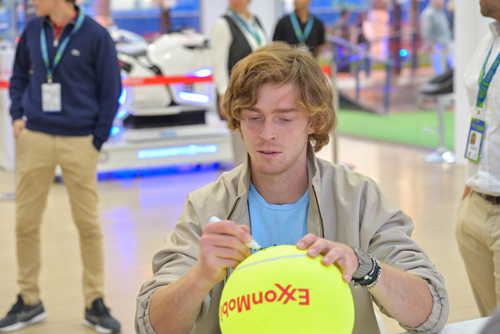 Andrey Rublev signs a giant tennis ball during his visit to ExxonMobil Qatar’s stand at Qatar ExxonMobil Open 2023 Public Village.