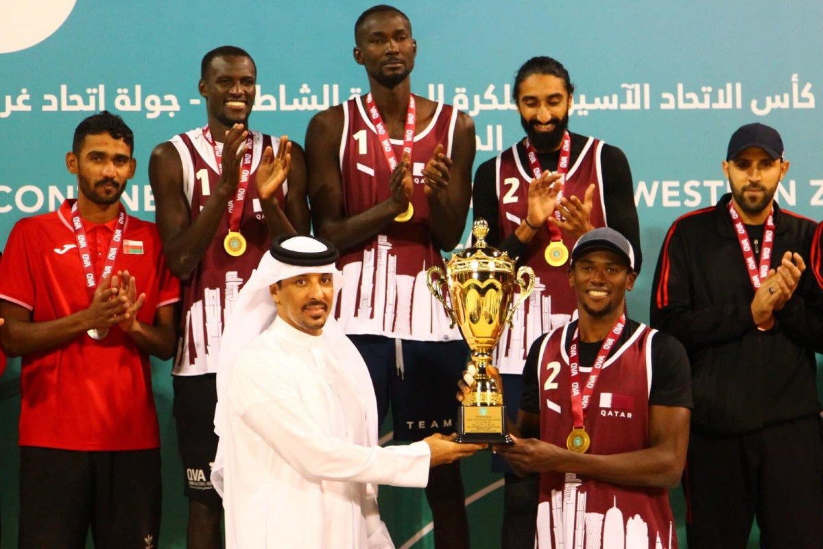 Ali Ghanem Al Kuwari, President of the Qatar and West Asia Volleyball Associations, presents the winner's trophy to Team Qatar's Ahmed Tijan.