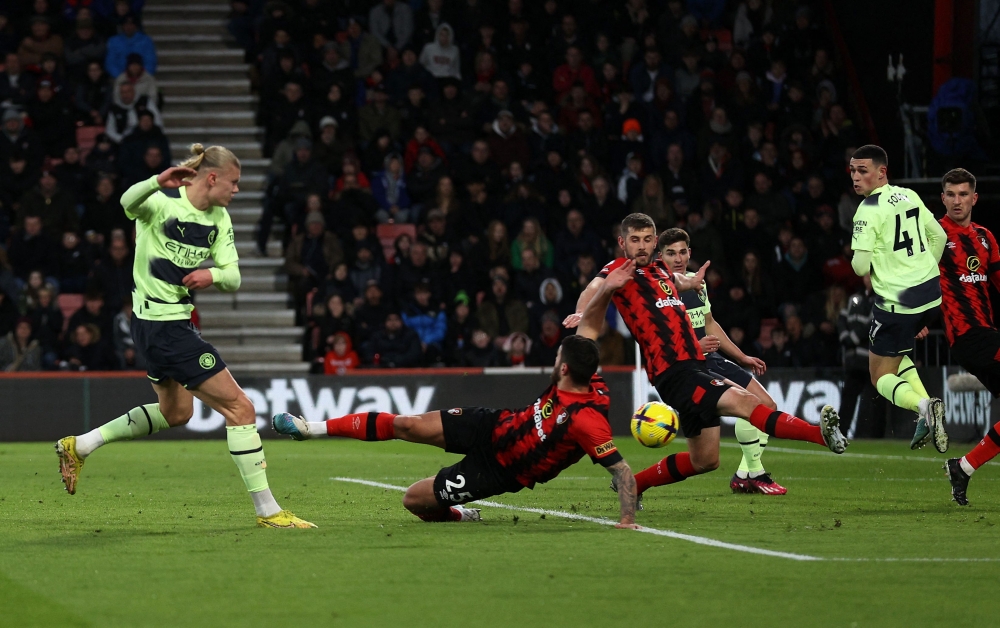 Manchester City's Norwegian striker Erling Haaland (left) has a shot on goal during the English Premier League football match between Bournemouth and Manchester City at the Vitality Stadium in Bournemouth, southern England on February 25, 2023. (Photo by ADRIAN DENNIS / AFP)