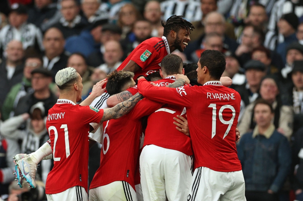 Manchester United's Brazilian midfielder Casemiro celebrates with teammates after scoring the opening goal of the English League Cup final football match between Manchester United and Newcastle United at Wembley Stadium, north-west London on February 26, 2023. (Photo by ADRIAN DENNIS / AFP)