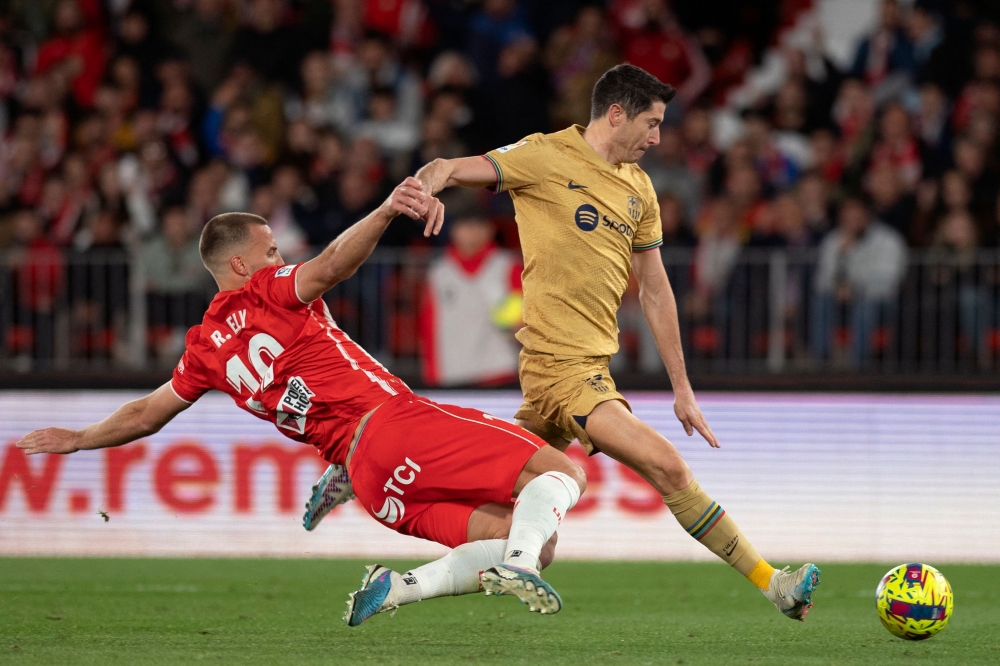 Almeria's Brazilian defender Rodrigo Ely (L) fights for the ball with Barcelona's Polish forward Robert Lewandowski during the Spanish League football match between UD Almeria and FC Barcelona at the Municipal Stadium of the Mediterranean Games in Almeria, on February 26, 2023. (Photo by JORGE GUERRERO / AFP)