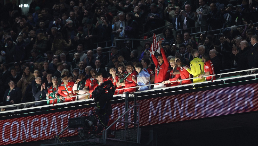 Manchester United's French defender Raphael Varane holds the trophy as Manchester United players celebrate their win after the English League Cup final football match between Manchester United and Newcastle United at Wembley Stadium, north-west London on February 26, 2023 (Photo by ADRIAN DENNIS / AFP)