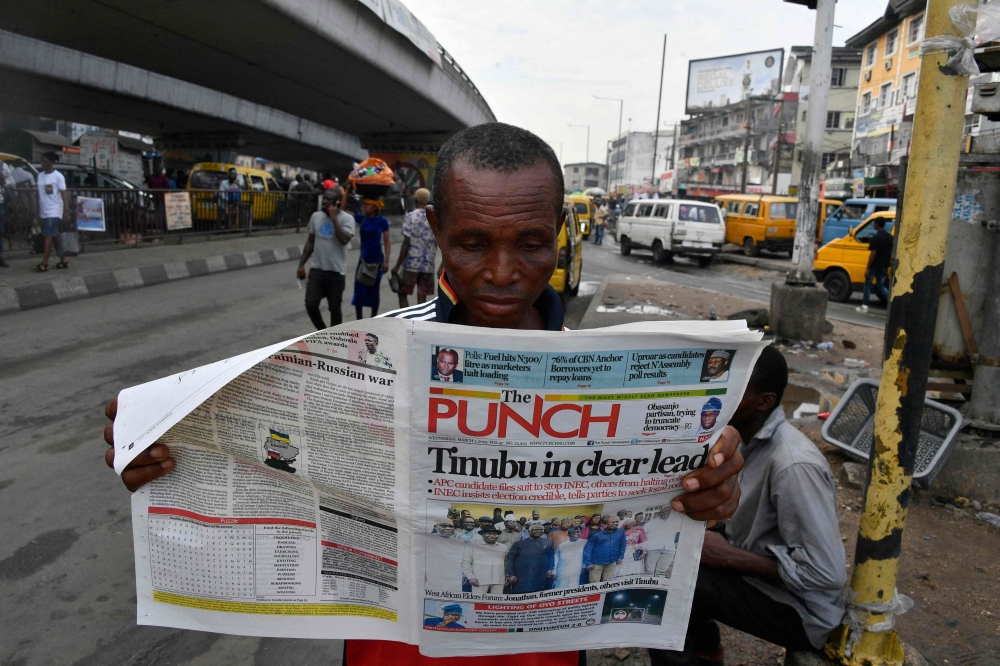A man reads newspaper at a newsstand as candidate of the ruling All Progressives Congress (APC) Bola Tinubu is declared President elect after the presidential election in Lagos, on March 1, 2023. (Photo by PIUS UTOMI EKPEI / AFP)