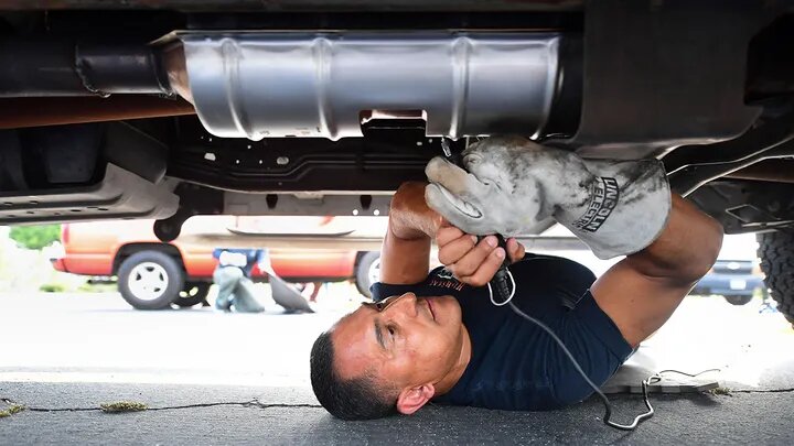 Deputy Jaime Moran from the Los Angeles Sheriffs Department engraves the catalytic converter of a vehicle with a traceable number on July 14, 2021, in City of Industry, California. File photo / AFP

