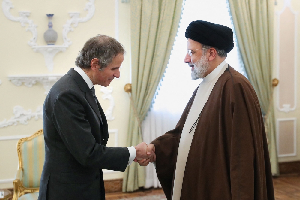 A handout picture provided by the Iranian presidency shows Iran's President Ebrahim Raisi welcoming International Atomic Energy Agency (IAEA) chief Rafael Grossi ahead of their meeting in Tehran on March 4, 2023. (Photo by ATTA KENARE / Iranian Presidency / AFP)