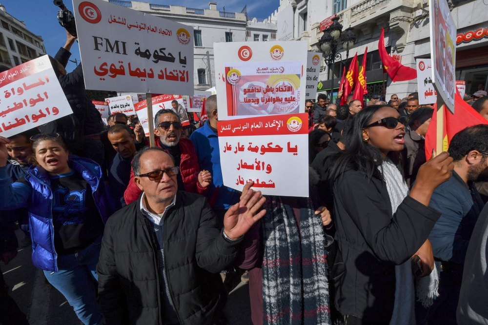 Demonstrators lift placards during an antigovernmental demonstration called for by the powerful trades union federation UGTT in Tunis, on March 4, 2023. (Photo by FETHI BELAID / AFP)