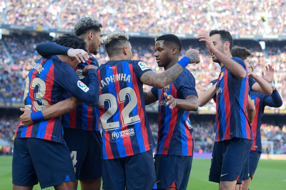 Barcelona's Brazilian forward Raphinha celebrates with teammates scoring his team's first goal during the Spanish League match between FC Barcelona and Valencia CF at the Camp Nou stadium in Barcelona on March 5, 2023. (Photo by Josep LAGO / AFP)