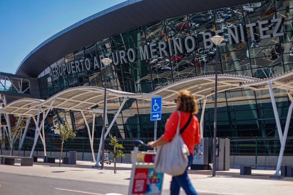 A passenger walks at Arturo Merino Benitez International Airport in Santiago on March 8, 2023, after an attempted robbery of more than 32 million US dollars from an armoured van which had just picked the money from a Latam Airline plane arriving from Miami.   (Photo by Karin POZO / AFP)