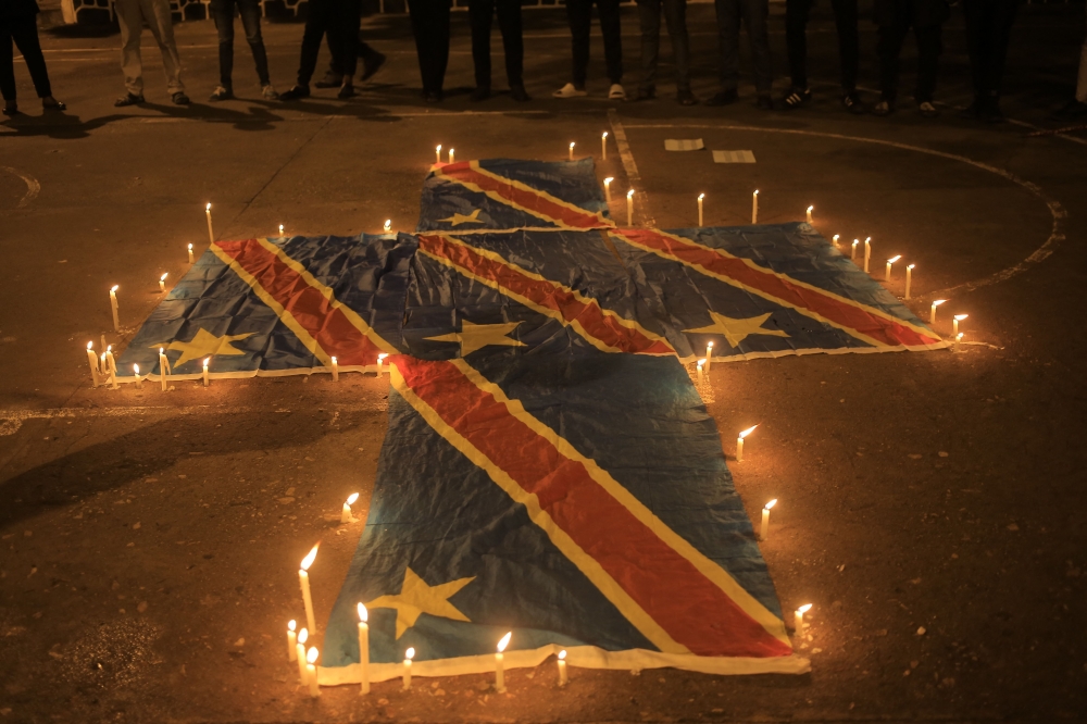In this file photo taken on December 07, 2022 flags of the Democratic Republic of Congo are surrounded by candles in Beni during a prayer vigil in remembrance of the victims of the ungoing unrest in the East of the country. (Photo by Sébastien KITSA MUSAYI / AFP)