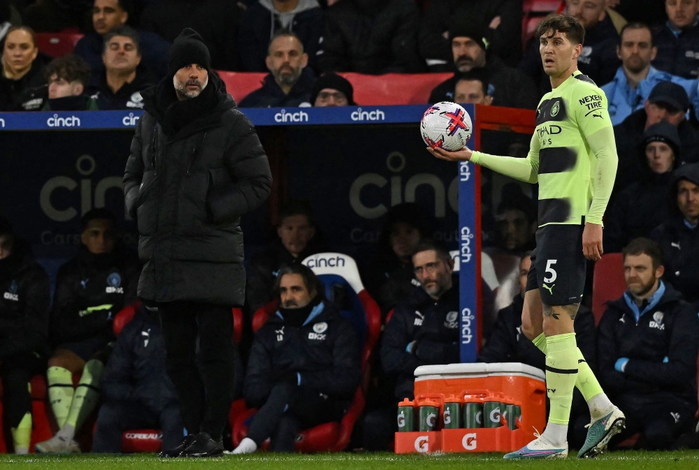 Manchester City's Spanish manager Pep Guardiola watches as Manchester City's English defender John Stones prepapres to take a throw-in during the English Premier League football match between Crystal Palace and Manchester City at Selhurst Park in south London on March 11, 2023. (Photo by Ben Stansall / AFP)