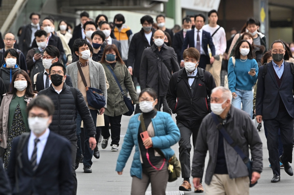 Commuters walk on a street in Shinjuku district of Tokyo on March 13, 2023 on the first day of reduced mask requirements. Photo by Kazuhiro NOGI / AFP