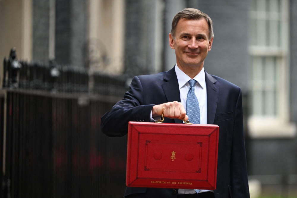 Britain's Chancellor of the Exchequer Jeremy Hunt poses with the red Budget Box as he leaves 11 Downing Street in central London on March 15, 2023, to present the government's annual budget to Parliament. (Photo by JUSTIN TALLIS / AFP)