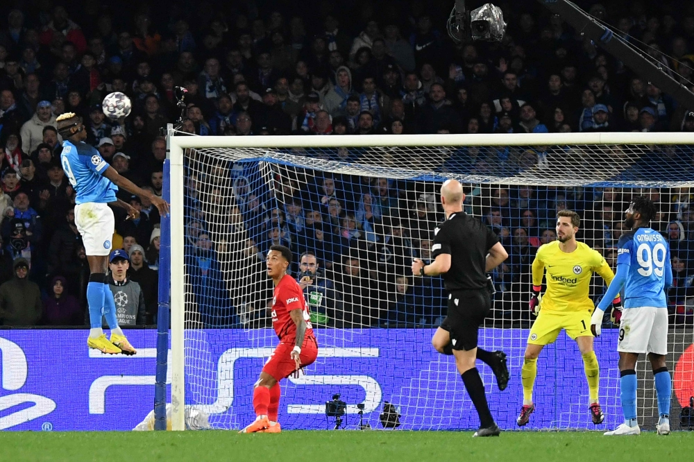Napoli's Nigerian forward Victor Osimhen (L) shoots a header to open the scoring during the UEFA Champions League round of 16, second leg football match between SSC Napoli and Eintracht Frankfurt at the Diego-Maradona stadium in Naples on March 15, 2023. (Photo by Tiziana FABI / AFP)