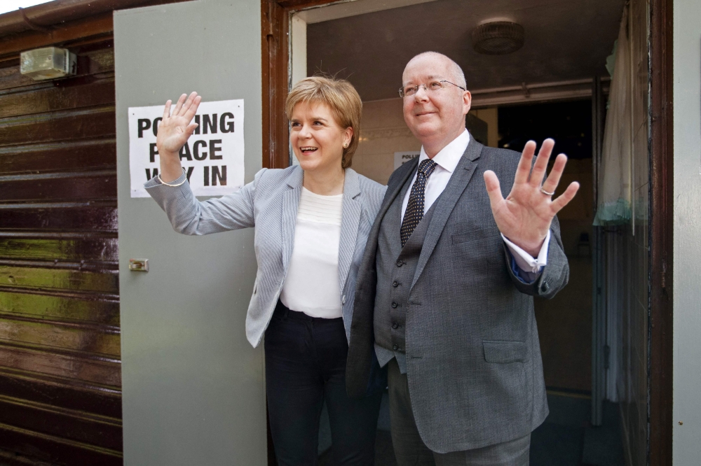 In this file photo taken on June 23, 2016 Scotland's First Minister and Leader of the Scottish National Party (SNP), Nicola Sturgeon (left) and her husband Peter Murrell, react as leave after casting their votes at a polling station at Broomhouse Community Hall in east Glasgow, as Britain holds a referendum on whether to stay or leave the European Union (EU). (Photo by Robert Perry / AFP)