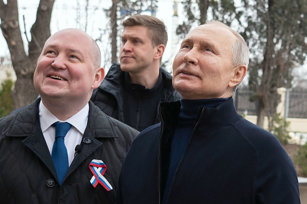 This handout photograph taken and released by the Russian presidential press office in Sevastopol on March 18, 2023, shows Russian President Vladimir Putin (R), talking to Sevastopol Governor Mikhail Razvozhayev (L), as he visits the Chersonesos Taurica historical and archeological park on the 9th anniversary of the referendum on the state status of Crimea and Sevastopol and its reunification with Russia. (Handout Photo / Russian Presidential Press Office / AFP) 