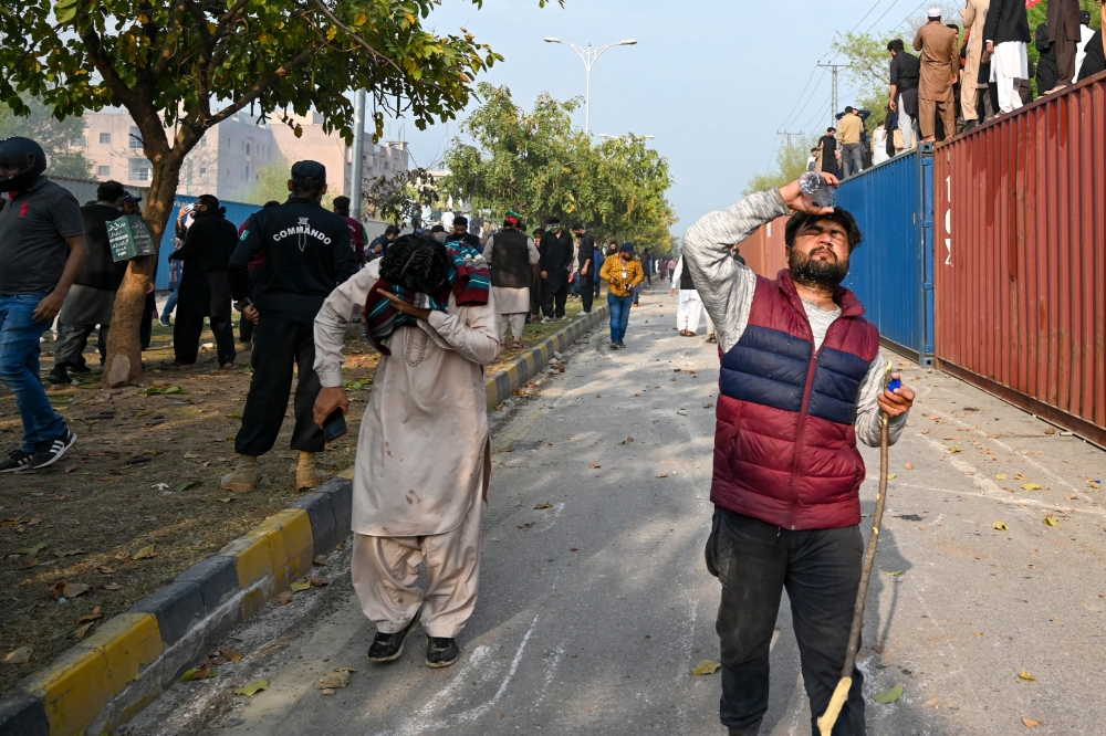 Pakistan's former Prime Minister Imran Khan's supporters run as police fire tear gas to disperse them outside a court in Islamabad on March 18, 2023.  (Photo by Farooq NAEEM / AFP)
 