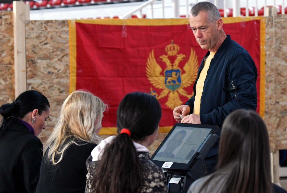 Election officials check documents of a Montenegrin voter at a polling station during the presidential election in Podgorica, on March 19, 2023.  (Photo by SAVO PRELEVIC / AFP)