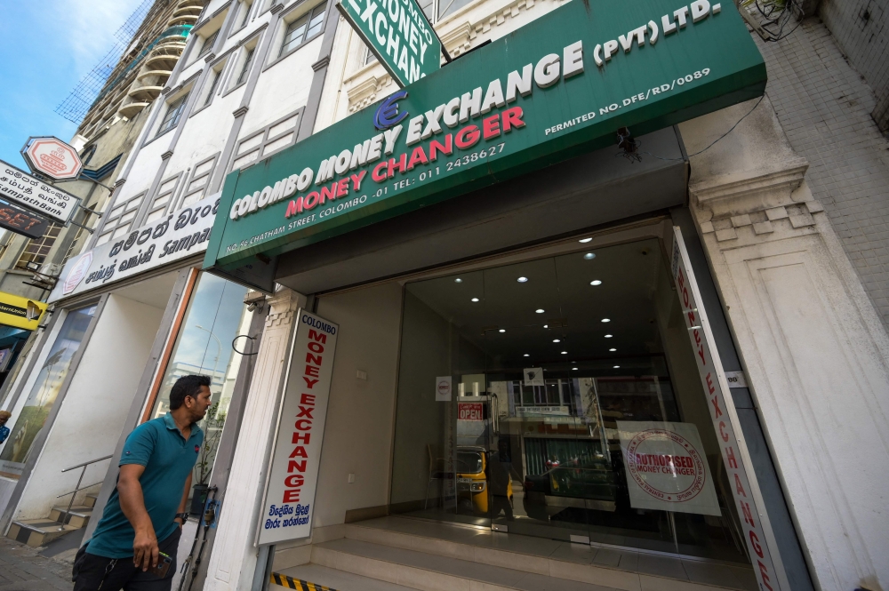 A Sri Lankan man walks past currency exchange shop in Colombo on March 20, 2023. - Cash-strapped Sri Lanka is seeking a 10-year moratorium on its foreign debt, President Ranil Wickremesinghe's office said on March 20 on the eve of a desperately needed $2.9 billion IMF bailout. (Photo by Ishara S. KODIKARA / AFP)