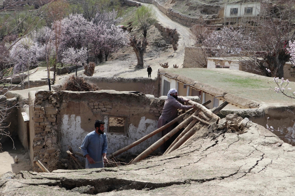 Residents remove debris from the rooftop of damaged a house at Sooch village in Jurm district of Badakhshan Province on March 22, 2023, following an overnight earthquake. (Photo by Omer Abrar / AFP)
