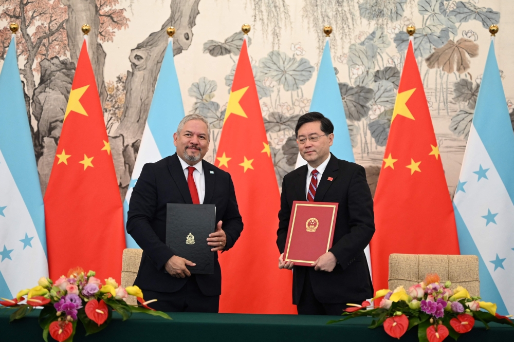 Honduras Foreign Minister Eduardo Enrique Reina (left) and Chinese Foreign Minister Qin Gang pose with documents following the establishment of diplomatic relations between the two countries, at a ceremony in the Diaoyutai State Guesthouse in Beijing on March 26, 2023. (Photo by GREG BAKER / AFP)