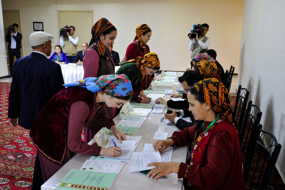 Voters receive their ballot papers at a polling station during Turkmenistan's parliamentary elections in the town of Annau, 20 km off the capital Ashgabat, on March 26, 2023. (Photo by Igor SASIN / AFP)