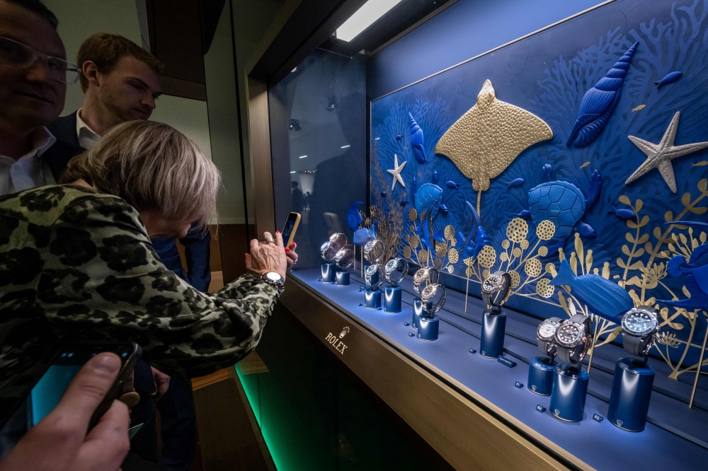Participants watches a showcase at the Rolex booth on the opening day of luxury watch fair 'Watches and Wonders Geneva', on March 27, 2023 in Geneva. (Photo by Fabrice Coffrini / AFP)