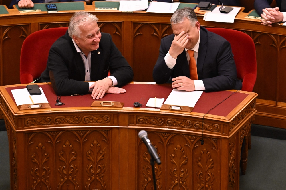 Hungarian Prime Minister Viktor Orban (right) and deputy prime minister Zsolt Semjen share a laugh as they attend the parliamenary session prior to the voting of representatives of the Hungarian Parliament about Finland's NATO accession, in the main hall of the parliament building in Budapest on March 27, 2023. (Photo by Attila Kisbenedek / AFP)