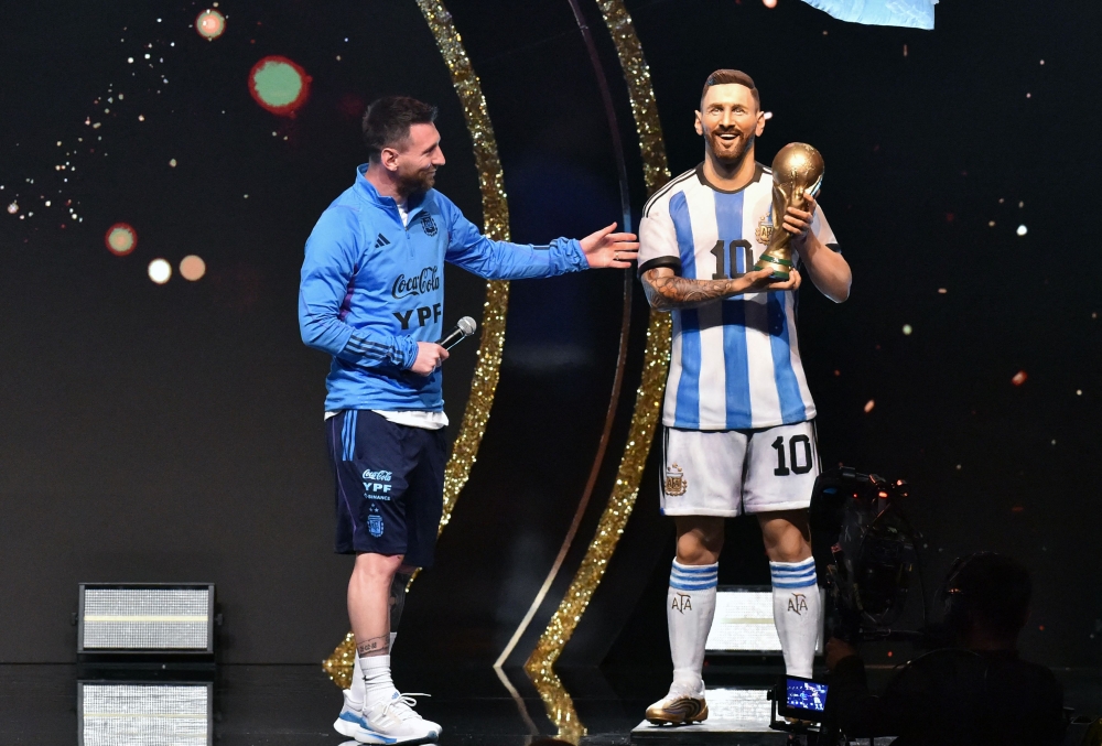 Argentina's forward Lionel Messi looks at a statue of himself during a tribute by Conmebol to the members of the Argentine national team for winning the Qatar 2022 World Cup, before the draw of the group phases of the Libertadores and Sudamericana football tournaments, at Conmebol's headquarters in Luque, Paraguay, on March 27, 2023. Photo by NORBERTO DUARTE / AFP