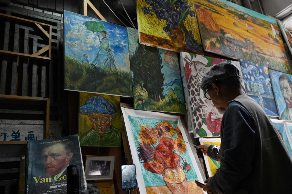 This picture taken on February 19, 2023 shows artist Deng Fei painting a replica of Vincent van Gogh's Sunflowers in an alley at Dafen village, in Shenzhen, in China southern Guangdong province. Photo by GREG BAKER / AFP