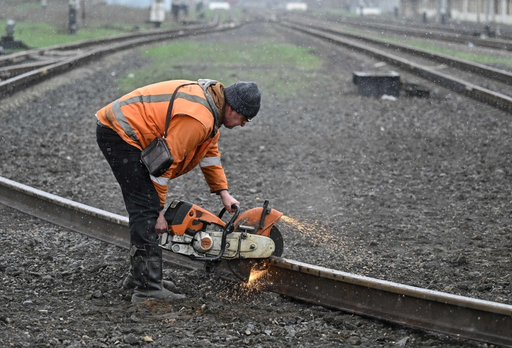 A railroad worker repairs damaged tracks after a strike in the town of Druzhkivka, Donetsk region on March 30, 2023, amid the Russian invasion of Ukraine. (Photo by Genya Savilov / AFP)