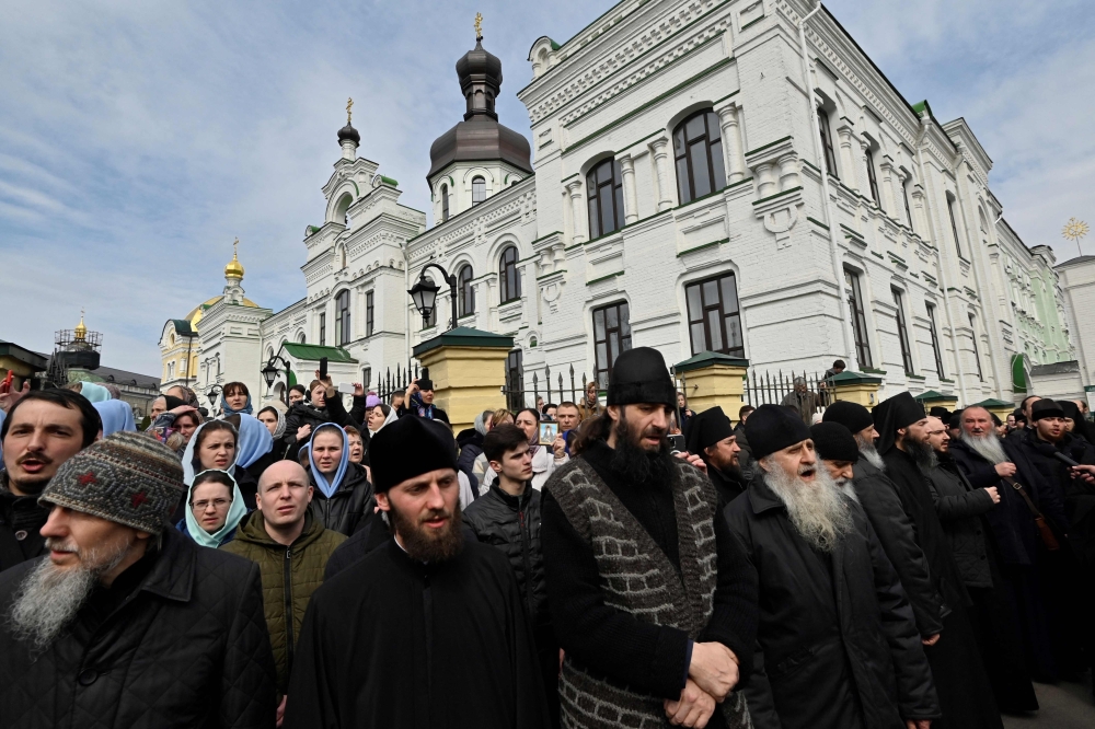 Believers of the Ukrainian Orthodox Church, accused of maintaining links with Moscow, pray outside the historic Kiev-Pechersk Lavra monastery in Kiev, on April 1, 2023. (Photo by Sergei CHUZAVKOV / AFP)
 