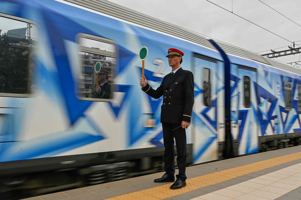 A station master holds a signalling disc as the first train since a deadly train disaster leaves from Athens' main station to Thessaloniki on April 3, 2023. Photo by Louisa GOULIAMAKI / AFP