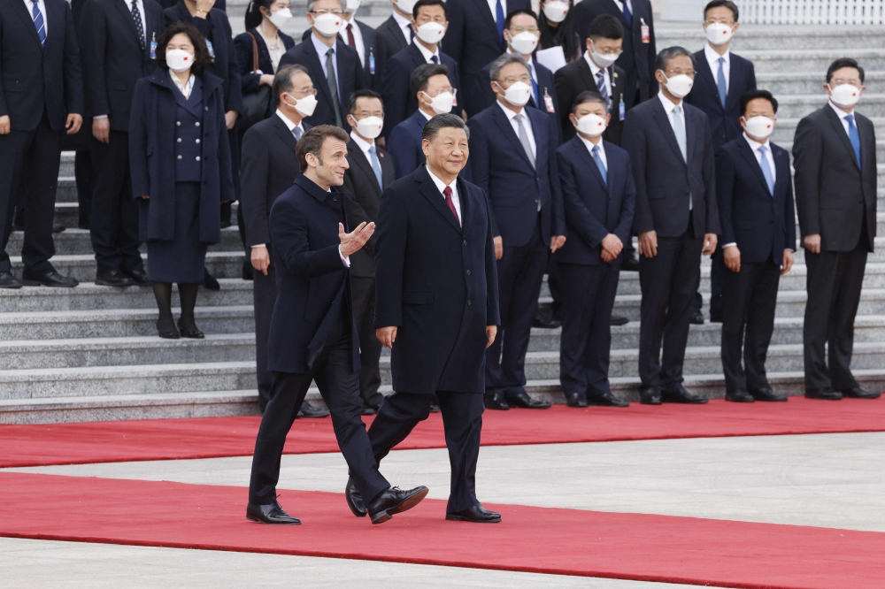 China's President Xi Jinping (C) and his French counterpart Emmanuel Macron arrive for the official welcoming ceremony in Beijing on April 6, 2023. (Photo by Ludovic Marin / AFP)