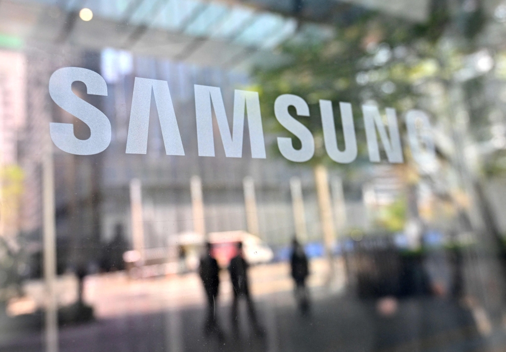 People walk past the Samsung logo displayed on a glass door at the company's Seocho building in Seoul on April 7, 2023. Photo by Jung Yeon-je / AFP